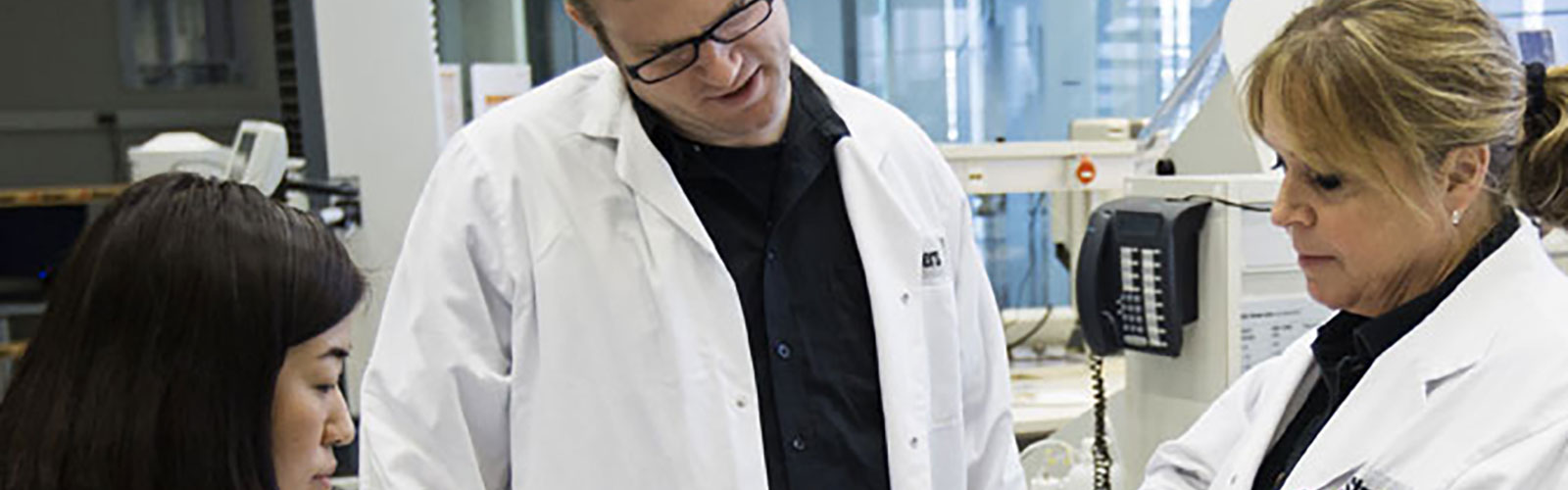 Application specialist in a lab with clients showing Struers solution
